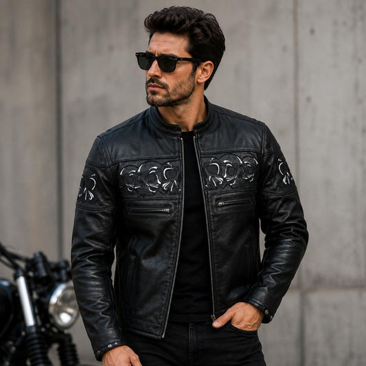 Man wearing a black leather jacket with decorative patterns, standing against a concrete wall.